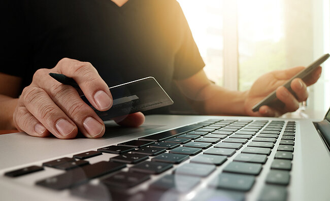 Een man zit achter een computer met een creditcard
